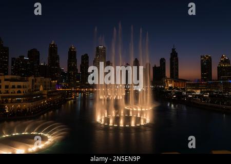 Dubai singende Brunnen bei Nacht Seeblick zwischen Wolkenkratzern. Moderne Architektur in der Dämmerung der Skyline der Stadt in der Innenstadt der Vereinigten Arabischen Emirate. Stockfoto