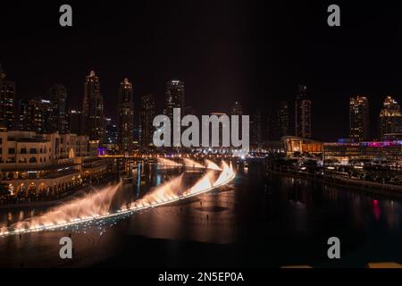 Dubai singende Brunnen bei Nacht Seeblick zwischen Wolkenkratzern. Moderne Architektur in der Dämmerung der Skyline der Stadt in der Innenstadt der Vereinigten Arabischen Emirate. Stockfoto