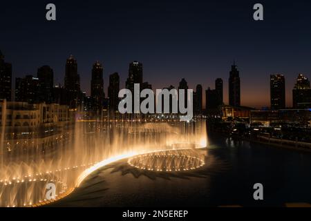 Dubai singende Brunnen bei Nacht Seeblick zwischen Wolkenkratzern. Moderne Architektur in der Dämmerung der Skyline der Stadt in der Innenstadt der Vereinigten Arabischen Emirate. Stockfoto