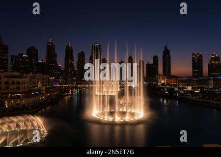 Dubai singende Brunnen bei Nacht Seeblick zwischen Wolkenkratzern. Moderne Architektur in der Dämmerung der Skyline der Stadt in der Innenstadt der Vereinigten Arabischen Emirate. Stockfoto