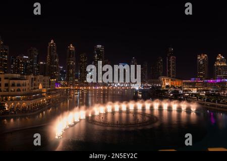 Dubai singende Brunnen bei Nacht Seeblick zwischen Wolkenkratzern. Moderne Architektur in der Dämmerung der Skyline der Stadt in der Innenstadt der Vereinigten Arabischen Emirate. Stockfoto