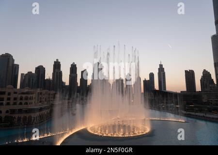 Dubai singende Brunnen bei Nacht Seeblick zwischen Wolkenkratzern. Moderne Architektur in der Dämmerung der Skyline der Stadt in der Innenstadt der Vereinigten Arabischen Emirate. Stockfoto