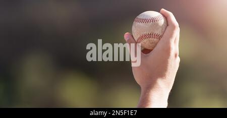 Männliche Hand hält Baseballball in einem Hintergrundstadion Stockfoto