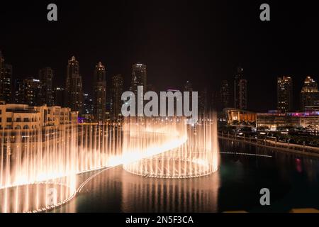 Dubai singende Brunnen bei Nacht Seeblick zwischen Wolkenkratzern. Moderne Architektur in der Dämmerung der Skyline der Stadt in der Innenstadt der Vereinigten Arabischen Emirate. Stockfoto