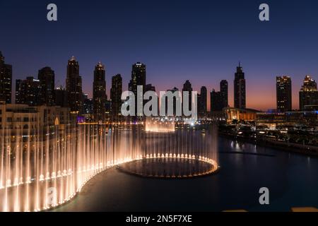 Dubai singende Brunnen bei Nacht Seeblick zwischen Wolkenkratzern. Moderne Architektur in der Dämmerung der Skyline der Stadt in der Innenstadt der Vereinigten Arabischen Emirate. Stockfoto