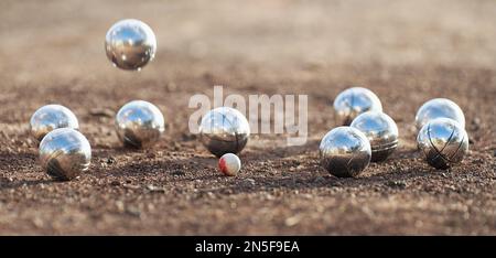 Petanque Ball Boules Schalen auf einem Staubboden, Foto beim Aufprall. Petanque-Spiel auf dem Boden. Bälle und ein kleiner Holzheber Stockfoto