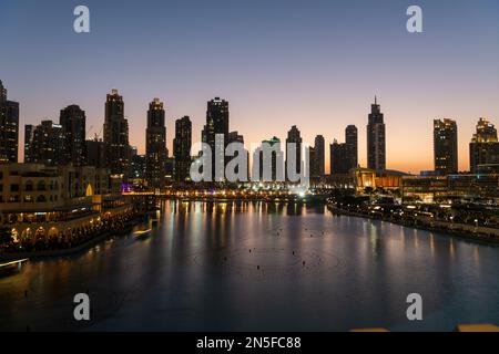 Dubai singende Brunnen bei Nacht Seeblick zwischen Wolkenkratzern. Moderne Architektur in der Dämmerung der Skyline der Stadt in der Innenstadt der Vereinigten Arabischen Emirate. Stockfoto