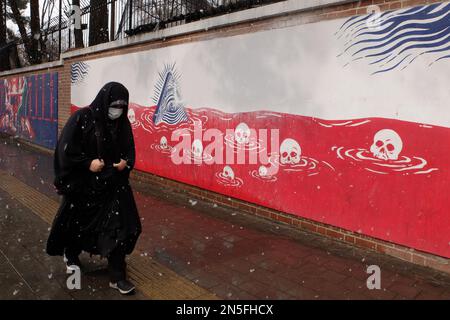 Teheran, Teheran, Iran. 9. Februar 2023. Eine iranische getarnte Frau in einem schwarzen Chador geht am 09. Februar 2023 an einem Wandgemälde entlang der Mauer der ehemaligen US-Botschaft vorbei, inmitten des Schnees in Teheran, Iran. Der Leiter der Atomaufsicht der Vereinten Nationen unterstrich die Dringlichkeit, die diplomatischen Bemühungen zur Begrenzung des iranischen Atomprogramms wiederzubeleben, und erklärte, dass sich die Situation schnell verschlechtern könnte, wenn die Verhandlungen scheitern. (Kreditbild: © RouzbritFouladi/ZUMA Press Wire) NUR REDAKTIONELLE VERWENDUNG! Nicht für den kommerziellen GEBRAUCH! Kredit: ZUMA Press, Inc./Alamy Live News Stockfoto