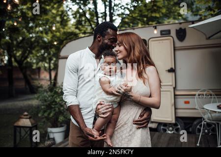 Gemischte Familien mit dunkelhäutigen Kleinkindern verbringen Zeit mit Umarmungen und Küssen im Campingpark. Ein afroamerikaner, seine schöne Frau und li Stockfoto