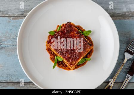 Béchamelsauce und Lasagne mit Hackfleisch auf einem Holztisch Stockfoto