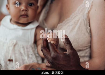 Gemischte Familie mit weißem Sohn und Tochter, die sich in einer gemütlichen Wohnung befindet. Ein afroamerikanischer Mann mit seiner hellhäutigen Frau Ki Stockfoto