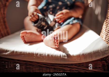 Ein kleines Mädchen in blauem Punktkleid hat positive Emotionen, wenn es auf einem Stock sitzt, hell und im Gesicht schattiert. afroamerikanisches Baby entspannt A Stockfoto