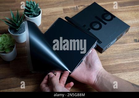 Samsung Galaxy Z Fold 4 in grau-grüner Farbe. Ein Mann packt das neue Handy aus. Stockfoto