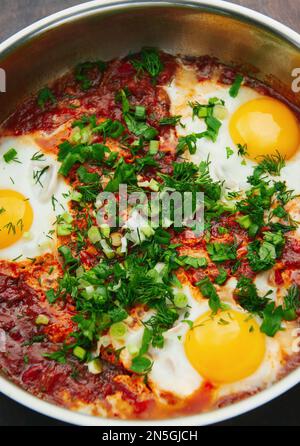 Leckeres und gesundes Shakshuka, nahöstliches Omelett in einer Bratpfanne. Leckeres Rührei in scharfer Tomatenpfeffersauce. Nahaufnahme Stockfoto