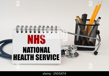 Medizinisches Konzept. Auf dem Tisch sind Bürobedarf, ein Stethoskop und ein Notizblock mit der Aufschrift - NHS- National Health Service Stockfoto