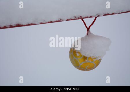 Schneebedeckte weihnachtsbälle, die an einer verschneiten Brückenschiene hängen Stockfoto