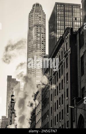 Rauch aus unterirdischer Heizung steigt in einer Straße in Midtown Manhattan, New York City, USA auf Stockfoto
