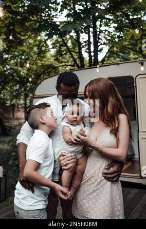 Gemischte Familien mit weißem Sohn und einer kleinen, zwergstarken Tochter verbringen Zeit zusammen im Camper Park. Ein afroamerikanischer Mann mit seinem hellhäutigen wi Stockfoto