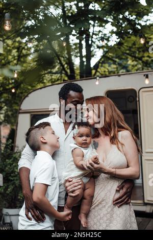 Gemischte Familien mit weißem Sohn und einer kleinen, zwergstarken Tochter verbringen Zeit zusammen im Camper Park. Ein afroamerikanischer Mann mit seinem hellhäutigen wi Stockfoto