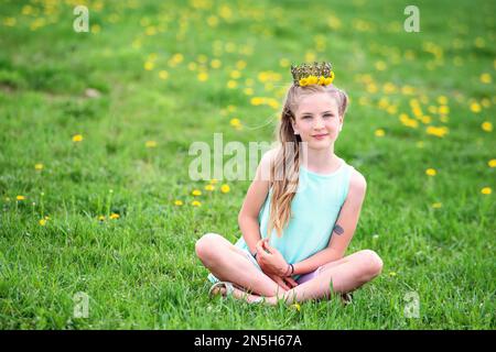 Hübsches blondes Tweedchen mit Löwenzahn auf einer Wiese. Stockfoto