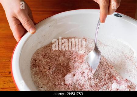 Hände rühren gemahlene Kräuter mit einem Löffel Stockfoto