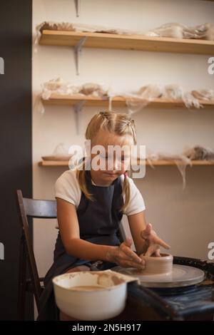 Das Mädchen sitzt am Potter's Wheel und kann Töpfercreat Stockfoto