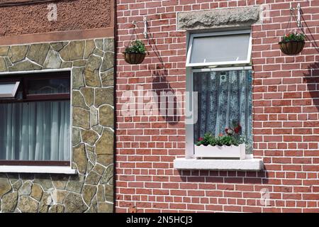 Außenfenster mit Ziegeln, Steinmauern und Blumen Stockfoto