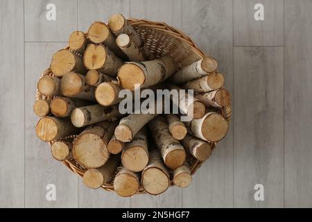 Korb aus Korb mit Kaminholz auf dem Boden im Innenbereich, Draufsicht Stockfoto