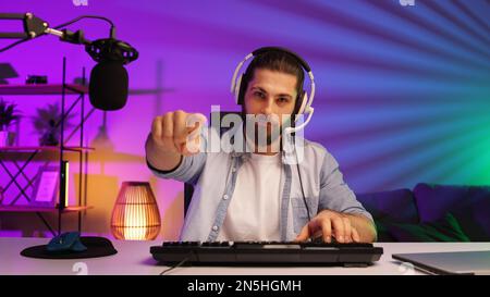 Cybersportler in einem Neonraum. Ein bärtiger Gamer, in Gaming-Kopfhörern, Herausforderungen. Lifestyle-Gamer, Online-Spiele. E Sport Stockfoto