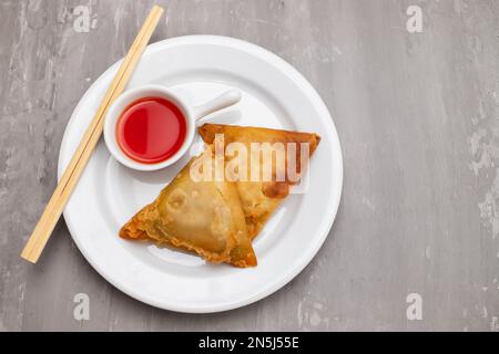 Zwei Samosas mit Fleisch und Gemüse auf einem kleinen weißen Teller Stockfoto