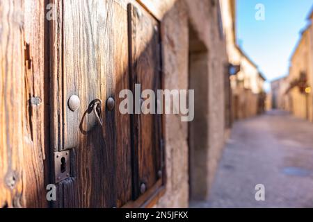 Alte Gasse mit Holzhäusern und altem Metallschloss an den Fenstern in Pedraza, Segovia. Stockfoto