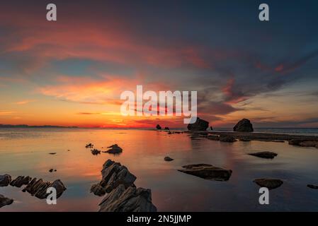 Die Sonne geht hinter den Felsen des Strandes Settefrati auf Sizilien unter Stockfoto