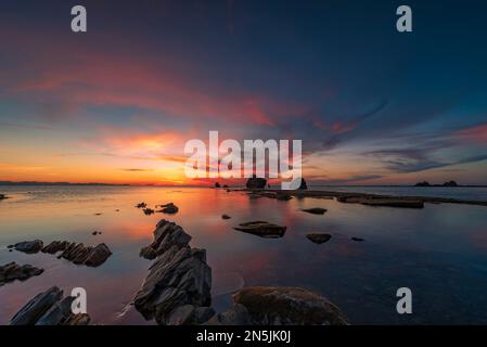 Die Sonne geht hinter den Felsen des Strandes Settefrati auf Sizilien unter Stockfoto