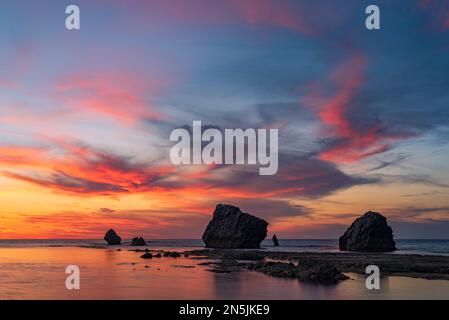 Die Sonne geht hinter den Felsen des Strandes Settefrati auf Sizilien unter Stockfoto