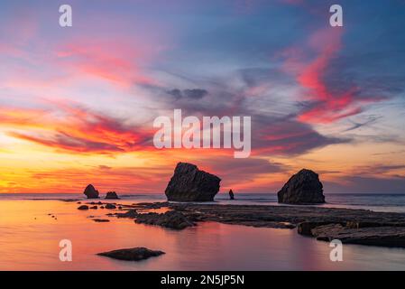 Die Sonne geht hinter den Felsen des Strandes Settefrati auf Sizilien unter Stockfoto