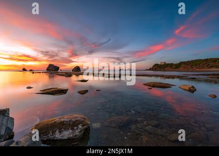 Die Sonne geht hinter den Felsen des Strandes Settefrati auf Sizilien unter Stockfoto