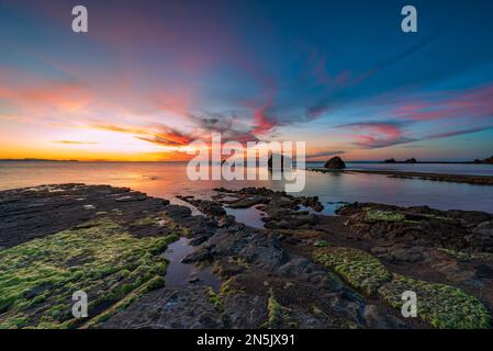 Die Sonne geht hinter den Felsen des Strandes Settefrati auf Sizilien unter Stockfoto