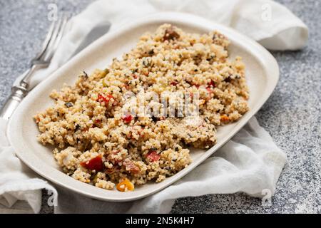 Couscous mit Gemüse in einem Gericht mit Gabel und Messer Stockfoto