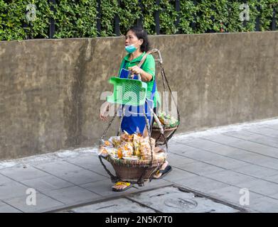 BANGKOK, THAILAND, FEBRUAR 04 2023, Ein Straßenverkäufer transportiert Lebensmittelkörbe Stockfoto