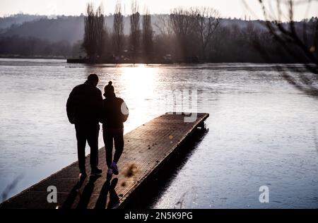 Stuttgart, Deutschland. 09. Februar 2023. Bei sonnigem Wetter gehen die Wanderer auf einer Fußgängerbrücke am Max Eyth Lake. Kredit: Christoph Schmidt/dpa/Alamy Live News Stockfoto