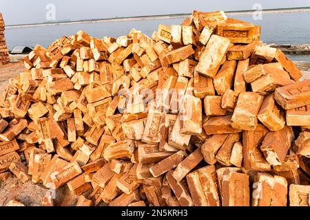 Ein Haufen roter Ziegelsteine, isoliert am Flusshintergrund. Stockfoto