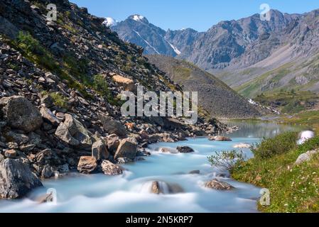 Alpenfluss Karakabak fließt an einem Sommertag über Felsen in der Nähe von Bergen von einem See in Altai in Sibirien hinunter. Stockfoto