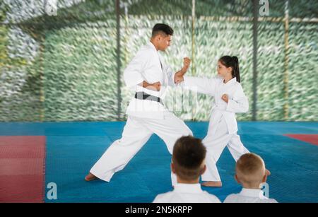 Ein Mädchen, das Karate mit Trainer auf Tatami im Freien übt Stockfoto