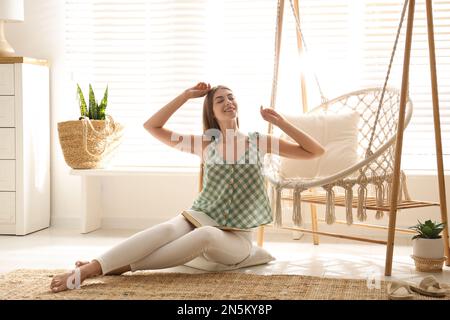 Eine Frau, die zu Hause in der Nähe eines bequemen Hängematte-Stuhls sitzt Stockfoto