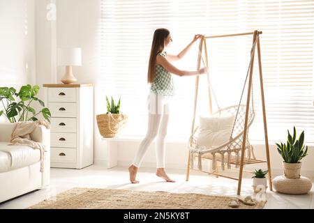 Eine Frau in der Nähe eines bequemen Hängematte-Stuhls zu Hause Stockfoto