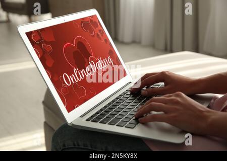 Frau besucht Dating-Seite über Laptop drinnen, Nahaufnahme Stockfoto