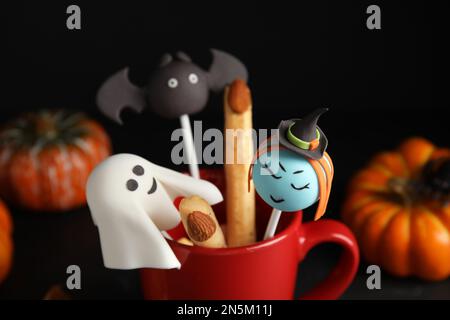 Verschiedene Tortenknöpfe im Becher, dekoriert als Monster, Nahaufnahme. Halloween-Leckerbissen Stockfoto