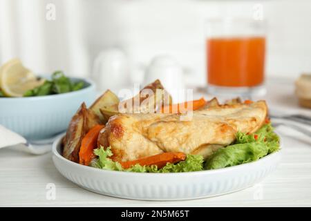 Köstliches gekochtes Hähnchen und Gemüse auf einem weißen Holztisch, Nahaufnahme. Gesunde Mahlzeiten aus der Airfryer Stockfoto