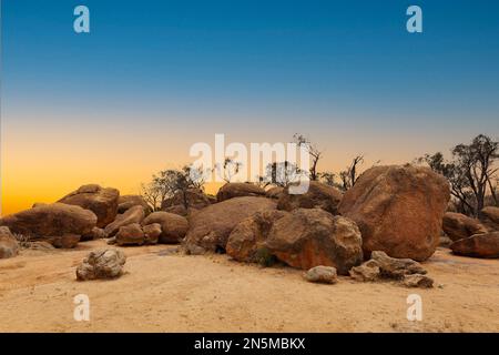 Landschaft bei Sonnenuntergang mit großen roten Felsbrocken auf dem Plateau über dem Wave Rock in der Nähe der Stadt Hyden in Westaustralien vor dem Hintergrund von Onkel Stockfoto