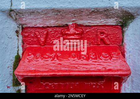 Ein roter britisch-viktorianischer Briefkasten in einer Wand. Stockfoto